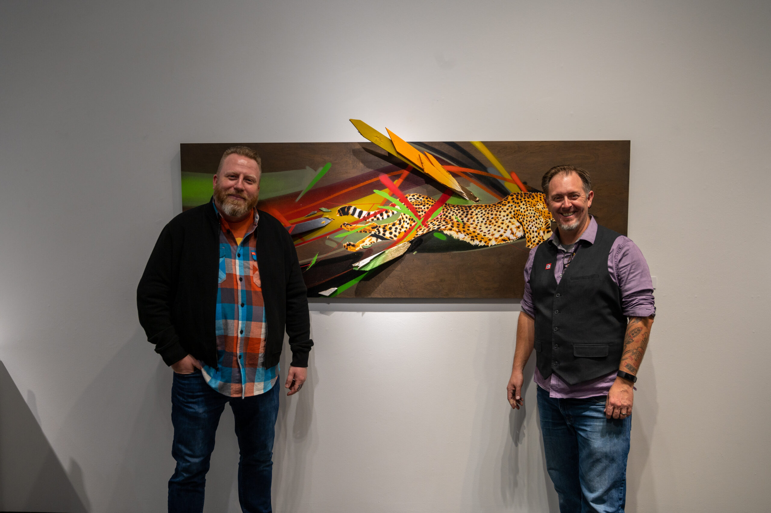 Photo of artists Bob Peck and Rich Cihlar in front of cheetah painting also known as Don't Panic!